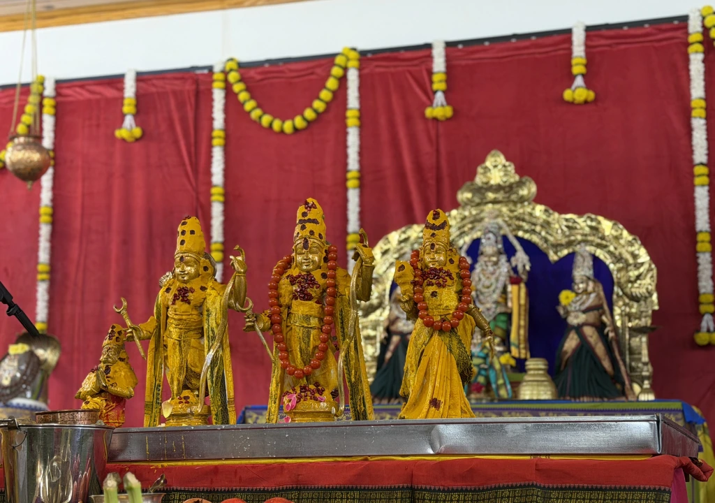 Hindu deities covered with turmeric and decorated during a temple ritual ceremony.